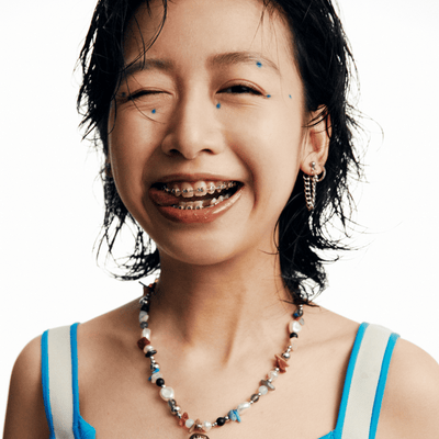 Person with braces and a colorful necklace on a white background