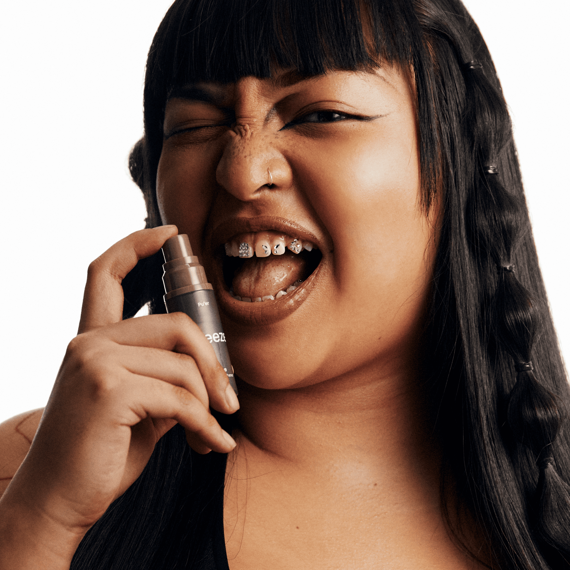 Person holding a makeup product close to their face with a neutral background