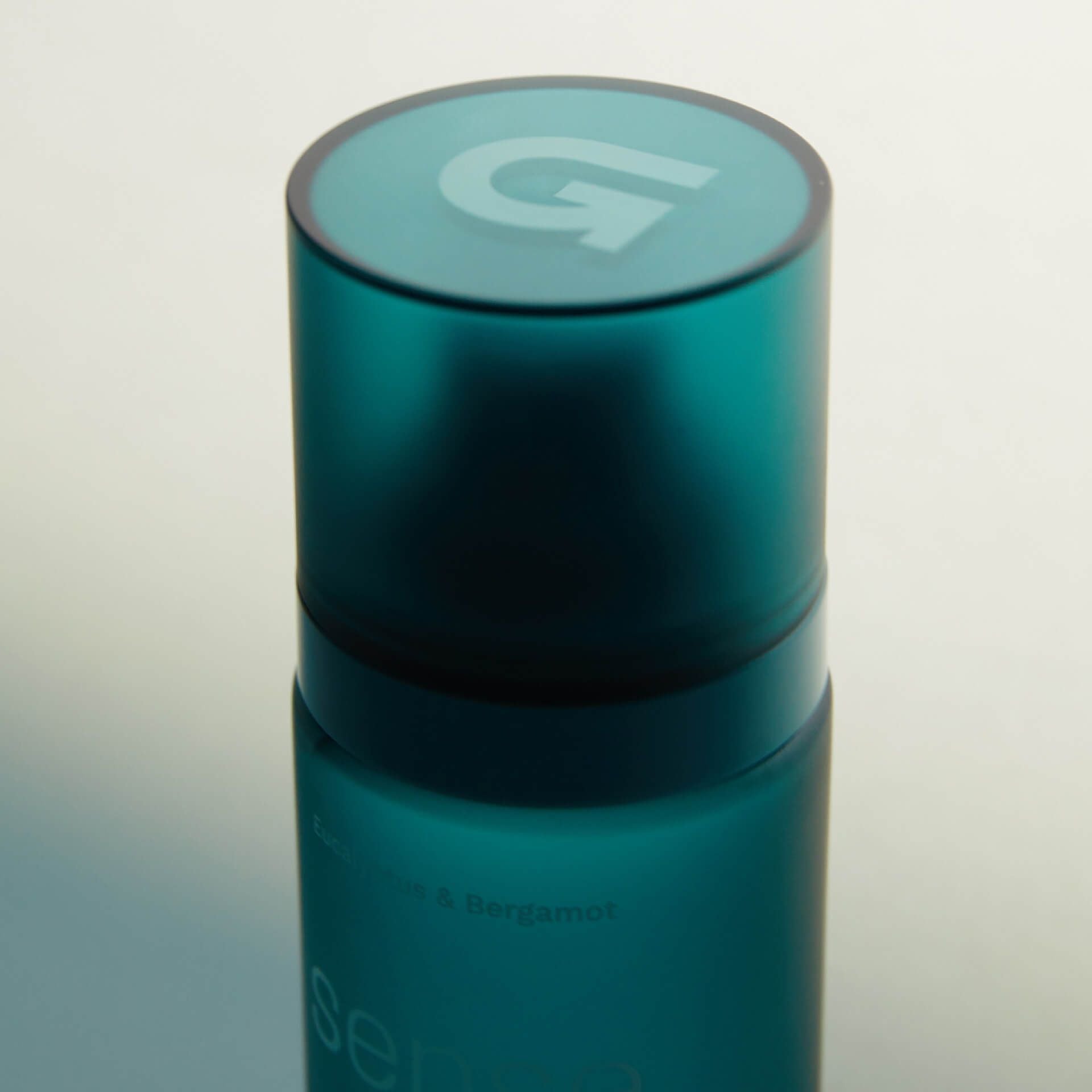 Teal cylindrical bottle with a logo on a white background