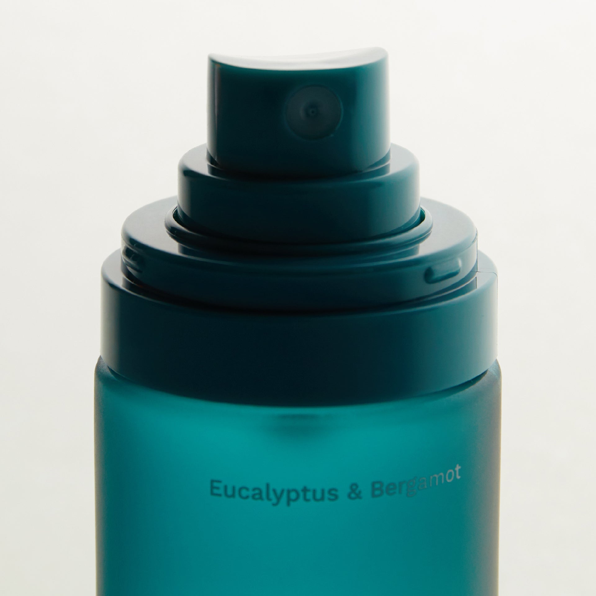A close-up of a green spray bottle labeled 'Eucalyptus & Bergamot' for deodorant.